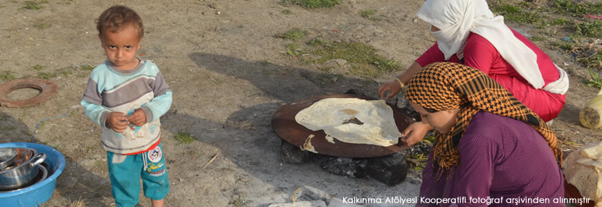 Sacda yemeklerini hazırlayan göçebe kadınlar ve fotoğrafçıya şaşkınlıkla bakan bir erkek çocuğu